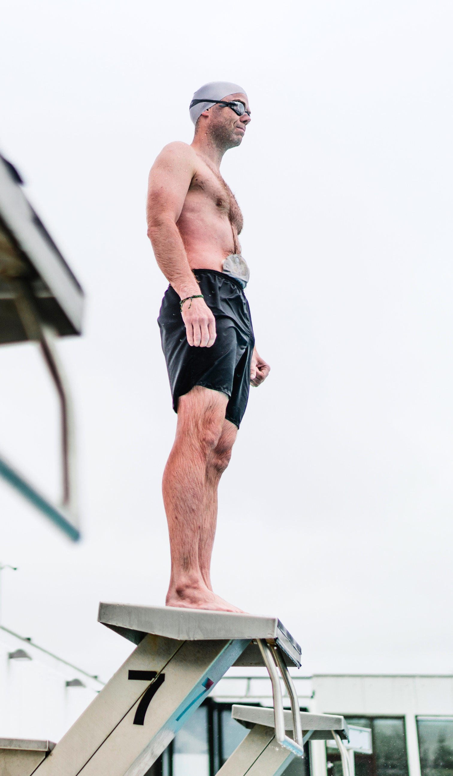 Grafika przedstawiająca osobę stojącą przy basenie w stroju kąpielowym, z delikatnym motywem wody w tle.